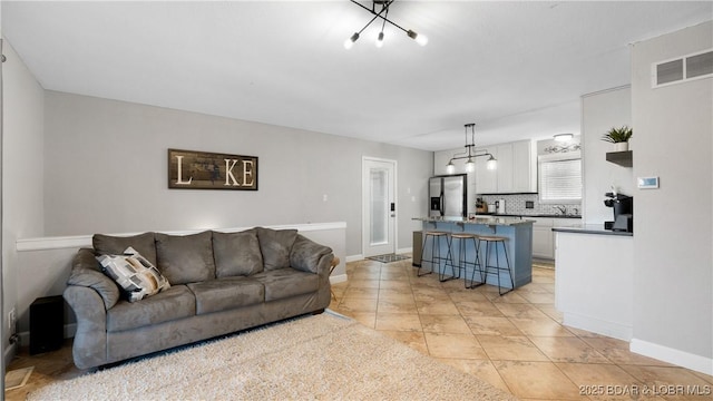 living room with light tile patterned flooring, visible vents, and baseboards