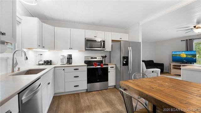 kitchen featuring a sink, stainless steel appliances, light countertops, white cabinets, and light wood-style floors