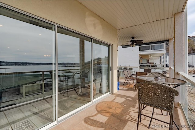 balcony with a sunroom, a ceiling fan, and outdoor dining space