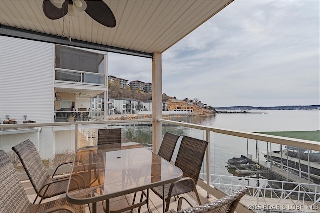 balcony with ceiling fan, outdoor dining area, and a water view