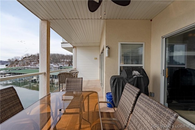 exterior space with grilling area, outdoor dining area, a water view, and a ceiling fan