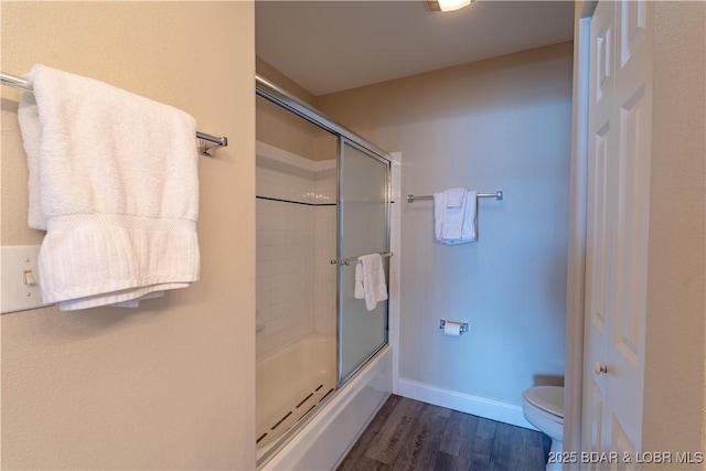 full bath with toilet, shower / bath combination with glass door, baseboards, and wood finished floors