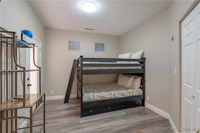 bedroom featuring visible vents, baseboards, and wood finished floors