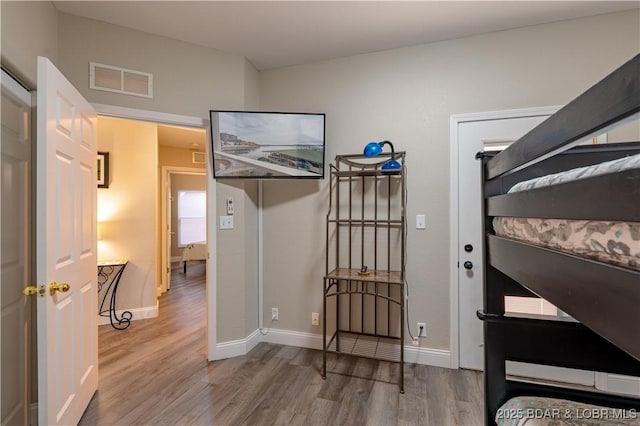 bedroom with wood finished floors, visible vents, and baseboards