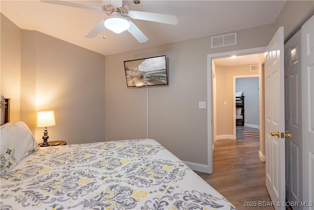 bedroom with a ceiling fan, wood finished floors, visible vents, and baseboards