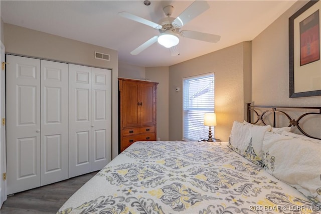 bedroom with ceiling fan, visible vents, dark wood finished floors, and a closet