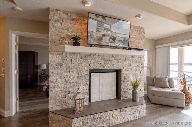 interior space featuring baseboards, a fireplace with raised hearth, and wood finished floors