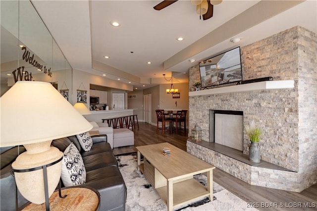 living room with baseboards, ceiling fan, wood finished floors, a fireplace, and recessed lighting