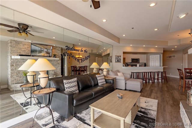 living room featuring a ceiling fan, recessed lighting, baseboards, and wood finished floors