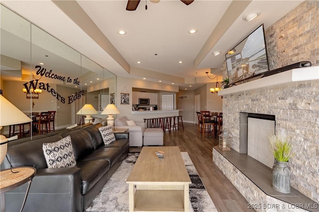 living room featuring a tile fireplace, recessed lighting, wood finished floors, a ceiling fan, and baseboards