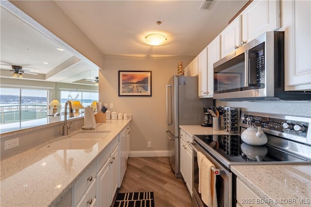 kitchen with visible vents, white cabinets, ceiling fan, stainless steel appliances, and a sink