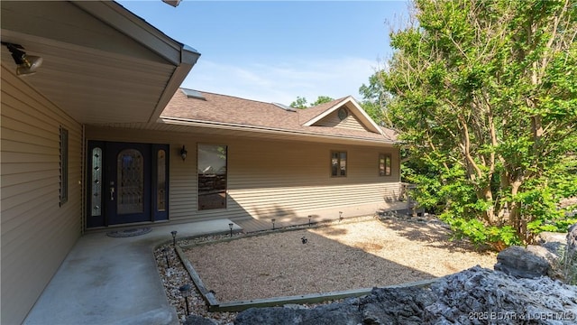 entrance to property with a shingled roof