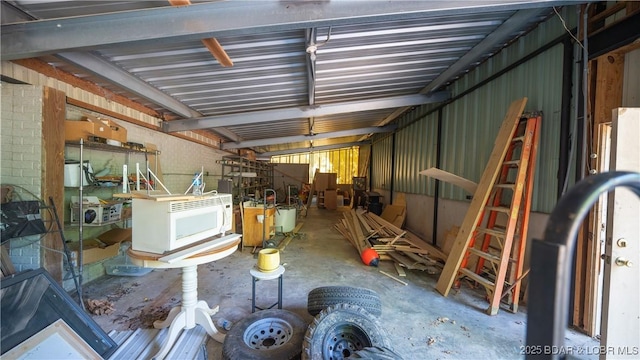 miscellaneous room with a garage, metal wall, and unfinished concrete floors