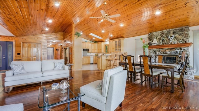 living room featuring wooden ceiling, vaulted ceiling, a stone fireplace, and wood finished floors