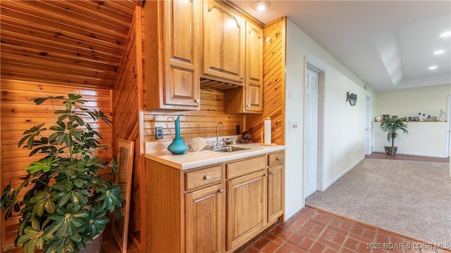 kitchen featuring brick floor, a sink, baseboards, light countertops, and dark carpet