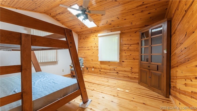 bedroom featuring light wood-type flooring, wooden ceiling, vaulted ceiling with skylight, and wood walls