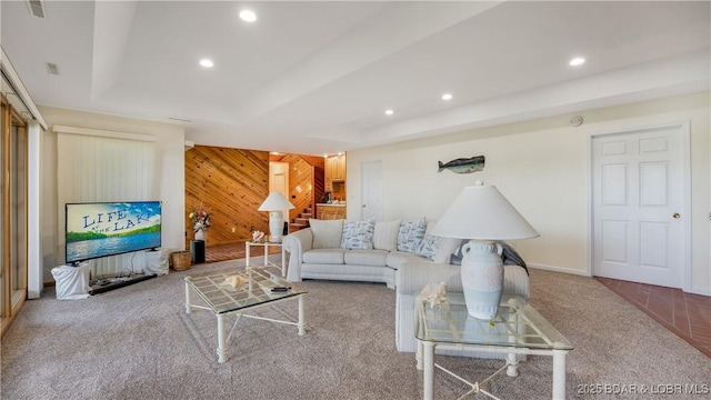living room featuring carpet floors, a tray ceiling, recessed lighting, wooden walls, and baseboards
