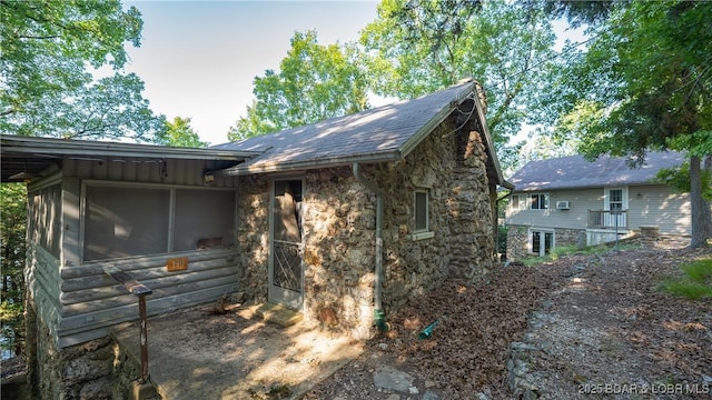 view of property exterior with a sunroom and stone siding