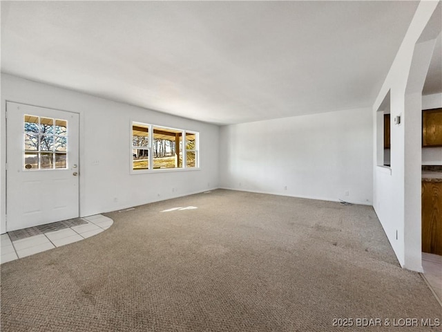 unfurnished living room featuring tile patterned flooring and carpet flooring