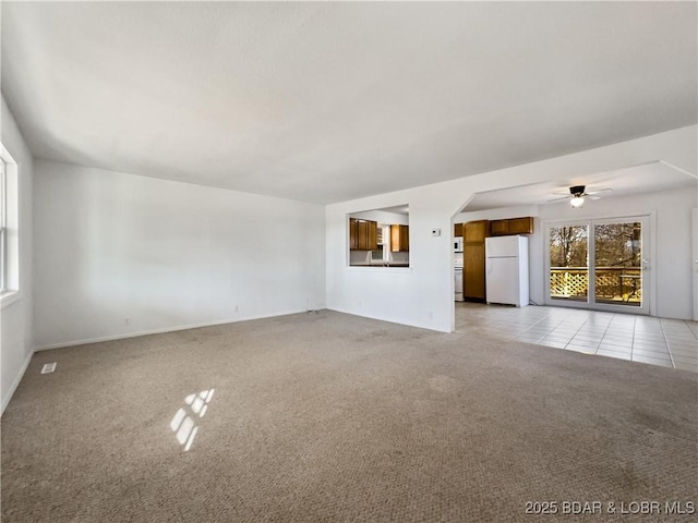 unfurnished living room with light carpet, light tile patterned floors, ceiling fan, and baseboards