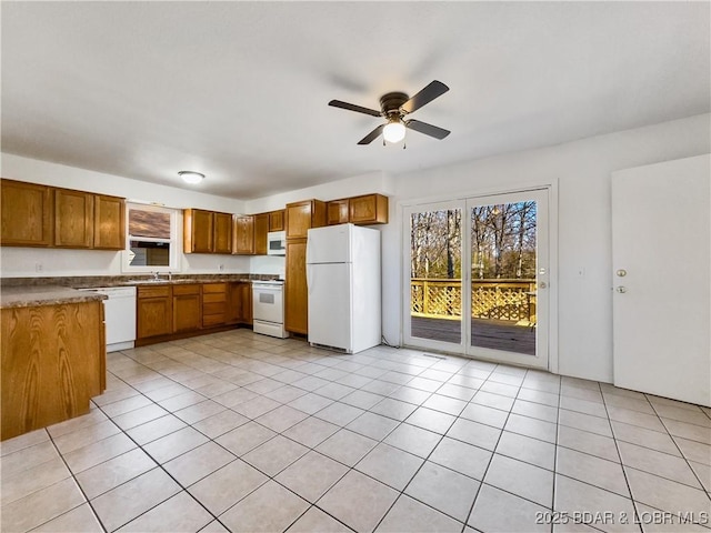 kitchen with white appliances, brown cabinets, a sink, and light tile patterned floors