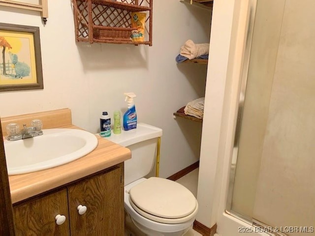 full bath featuring a shower with shower door, toilet, and vanity