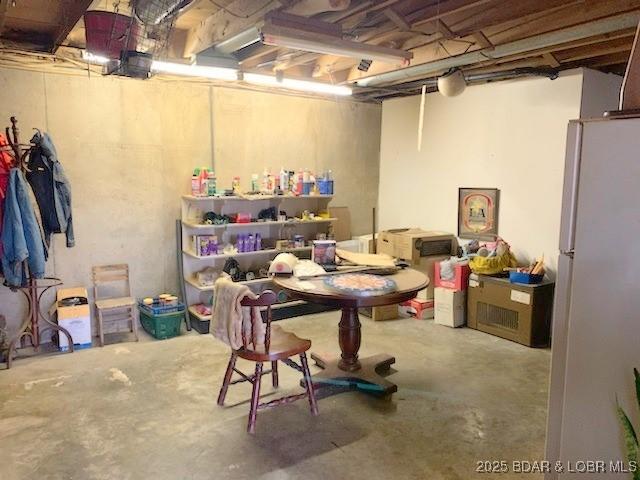 unfinished basement with freestanding refrigerator