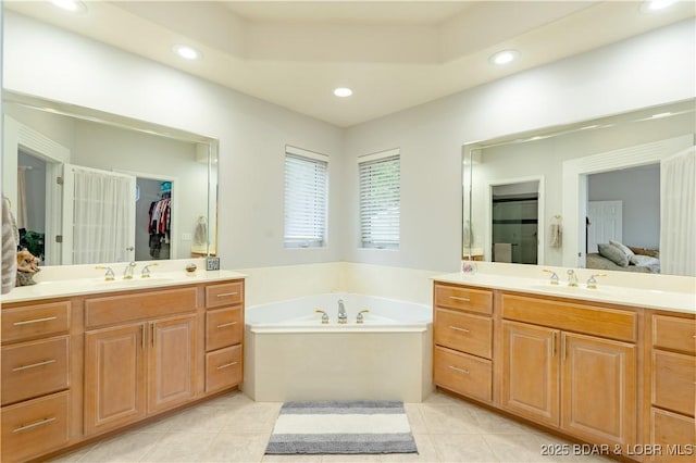 bathroom featuring a garden tub, two vanities, a sink, and tile patterned floors