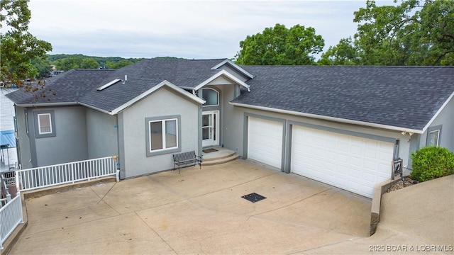 single story home with driveway, roof with shingles, an attached garage, and stucco siding