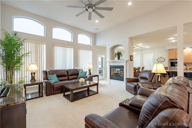 living room with a ceiling fan, recessed lighting, light colored carpet, and a multi sided fireplace