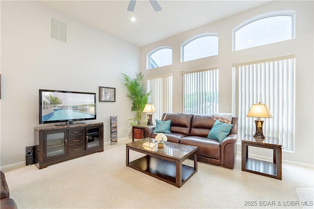 carpeted living area featuring a towering ceiling, baseboards, and visible vents