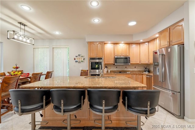 kitchen with appliances with stainless steel finishes, a breakfast bar, light tile patterned flooring, and light stone countertops