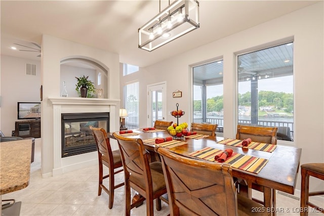 dining space with light tile patterned floors, plenty of natural light, visible vents, and a multi sided fireplace