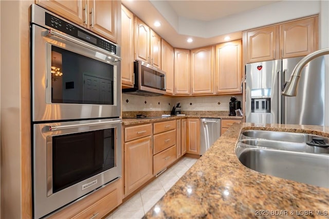 kitchen featuring light tile patterned floors, recessed lighting, light brown cabinetry, appliances with stainless steel finishes, and a sink