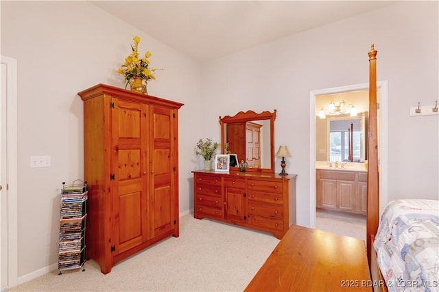 bedroom with baseboards, light colored carpet, connected bathroom, and a sink