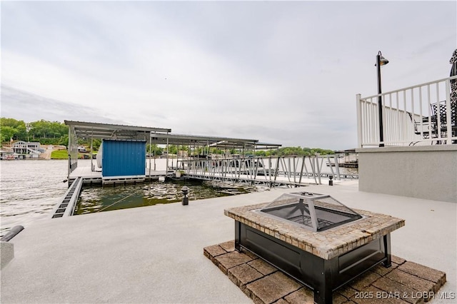 view of patio / terrace featuring a water view, a floating dock, and an outdoor fire pit