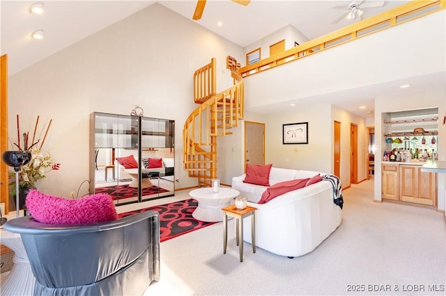 living room featuring stairway, ceiling fan, high vaulted ceiling, and light colored carpet