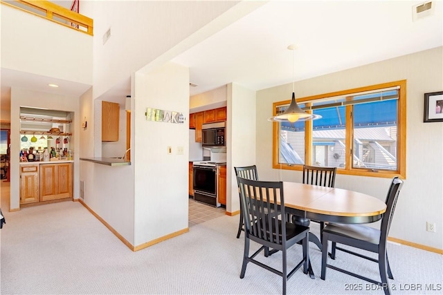 dining area featuring baseboards, visible vents, and light colored carpet