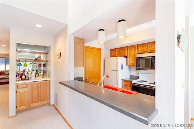 kitchen with white appliances, visible vents, dark countertops, a peninsula, and a sink