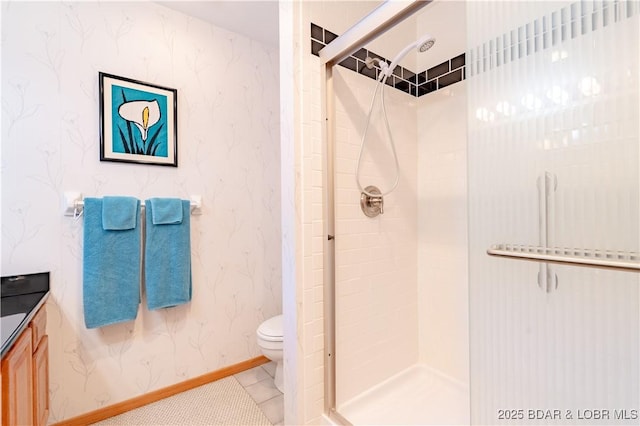 bathroom featuring baseboards, a shower stall, toilet, and wallpapered walls