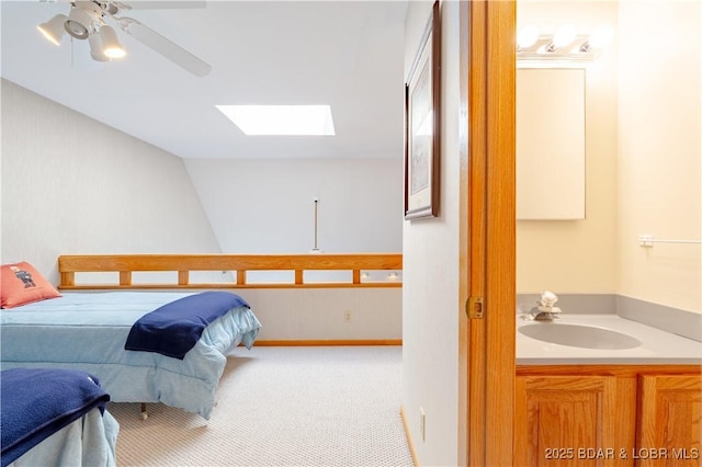 bedroom featuring a skylight, a ceiling fan, a sink, and carpet flooring