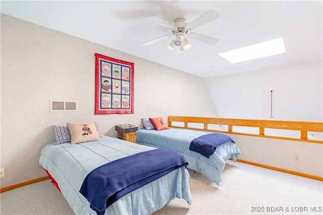 carpeted bedroom featuring a ceiling fan, visible vents, lofted ceiling with skylight, and baseboards