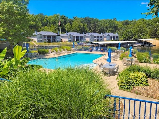 pool with a patio, fence, and a residential view