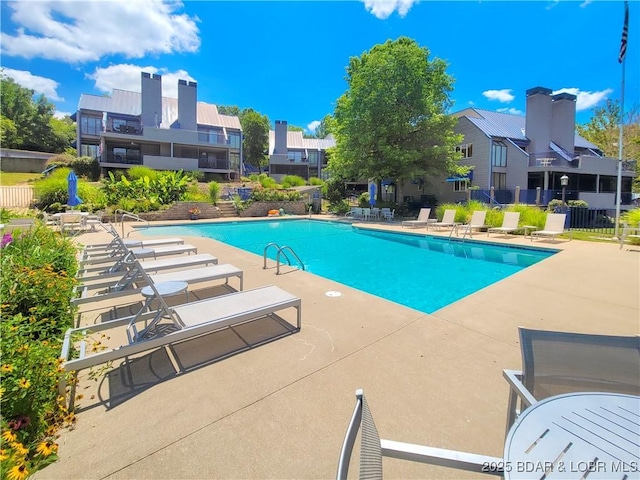 pool with a residential view, a patio area, and fence