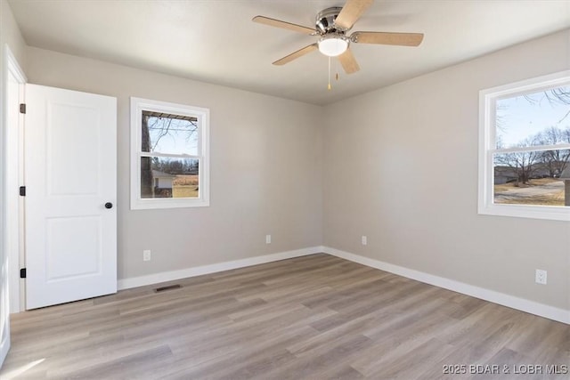 spare room featuring a wealth of natural light, visible vents, and baseboards