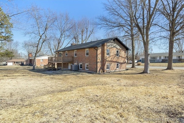 rear view of house featuring brick siding, a wooden deck, stairs, central AC unit, and a chimney