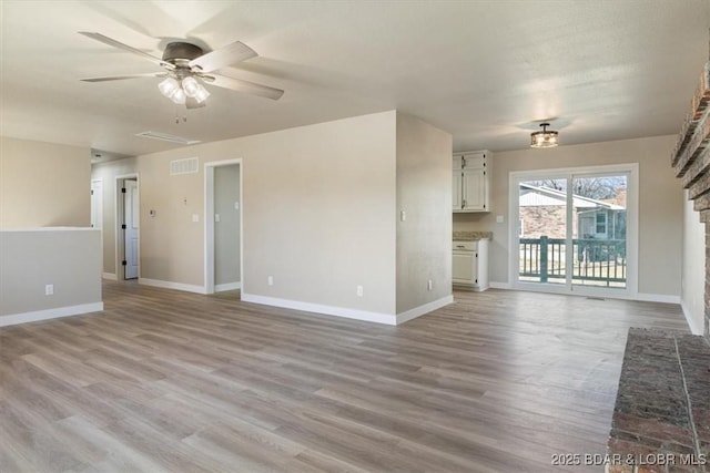 unfurnished living room with visible vents, baseboards, ceiling fan, light wood-style floors, and a brick fireplace