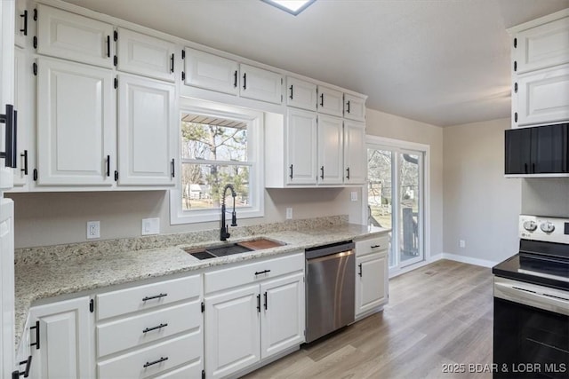 kitchen featuring a sink, appliances with stainless steel finishes, white cabinets, light wood finished floors, and light stone countertops