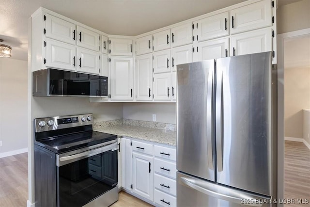 kitchen with light wood finished floors, appliances with stainless steel finishes, and white cabinetry