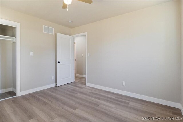 unfurnished bedroom with visible vents, baseboards, wood finished floors, a closet, and a ceiling fan